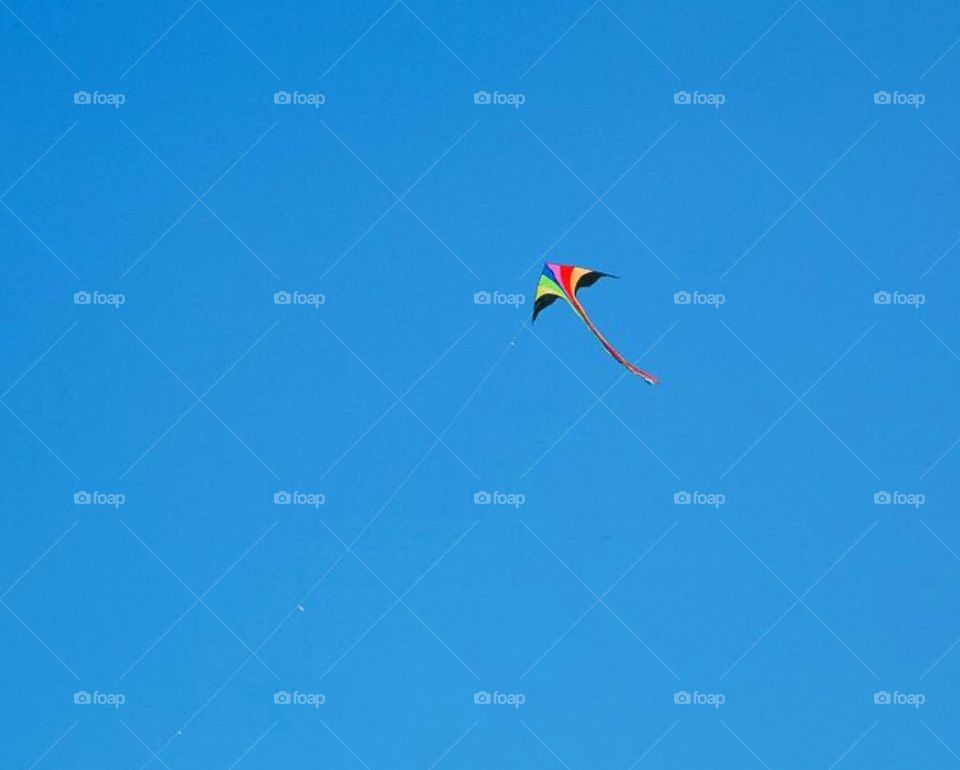 colorful, bright, small kite flies against the blue sky, minimalism 