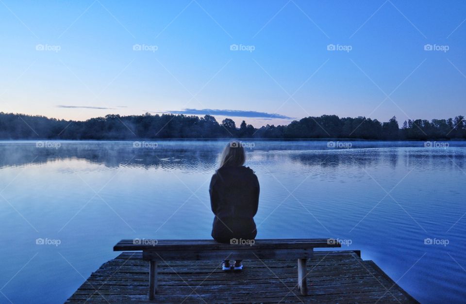 woman sitting on thd bench at the lake in boreczno, poland