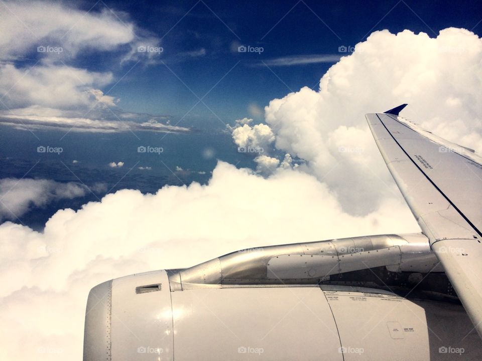Flying High. View of clouds from an airplane window showing part of the wing and engine