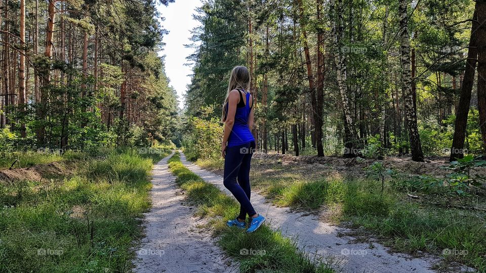 woman in running clothes on forest path