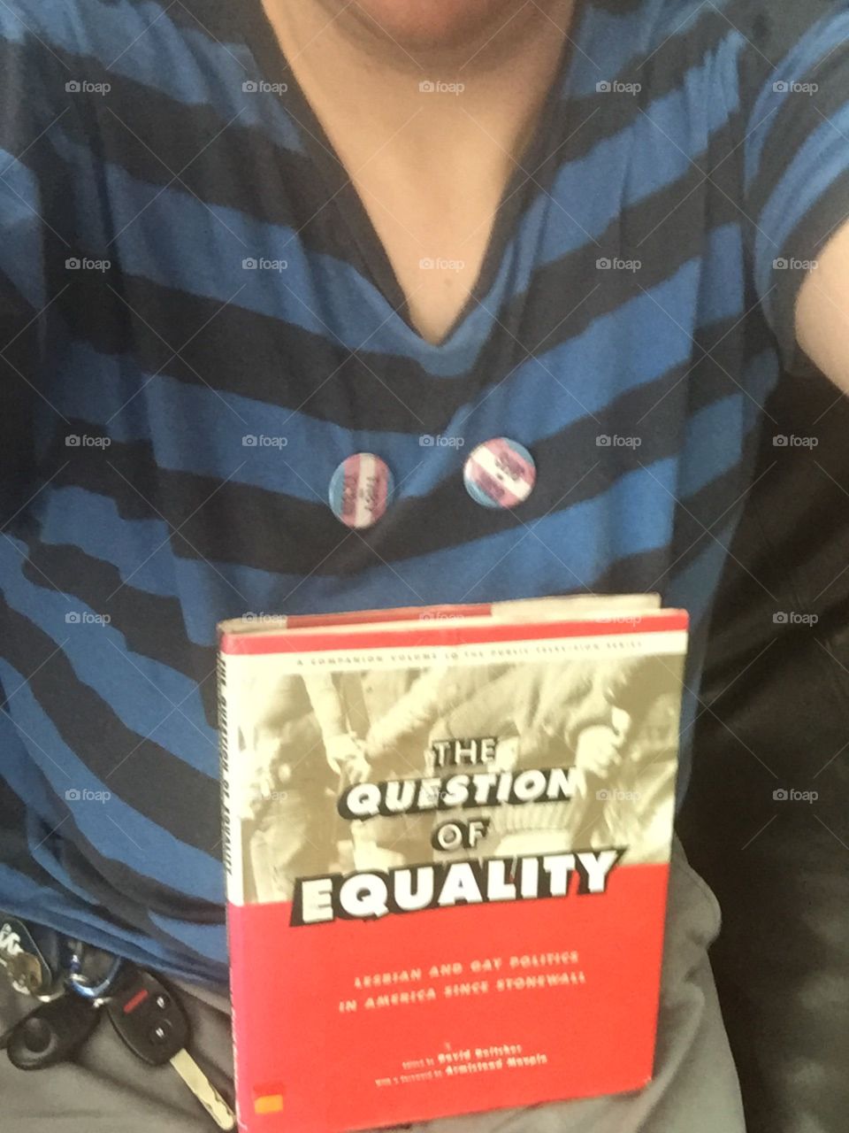 It’s a photo of a they/them and she/her pronoun buttons, plus the cover of the book “the question of equality: lesbian and gay politics...” re the stonewall riots 1960’s origins of modern pride weeks across the modern world in the 20th century etc 