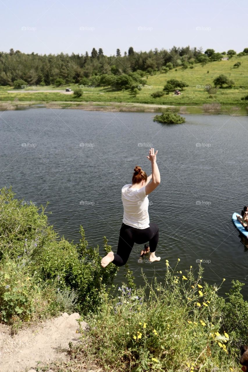 Woman jump from the cliff to the lake 