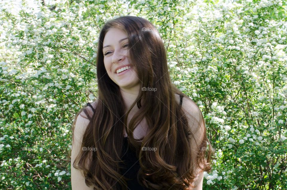 Smiling woman brunette with beautiful natural hair on background of flowers