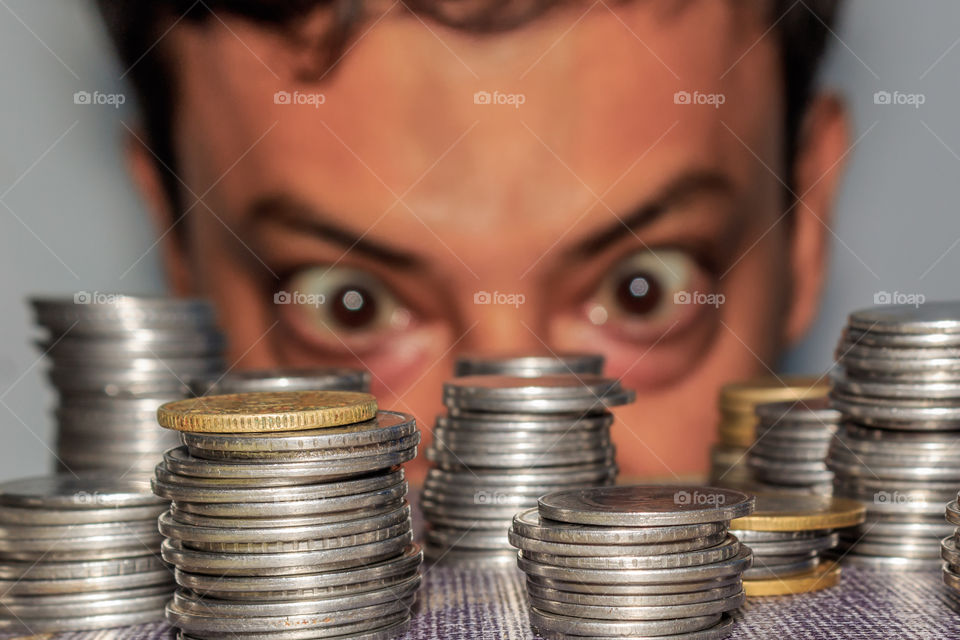 Focus on Coin. A rich greedy elderly man looks at coins. The collector looks at his wealth. An elderly man staring at metal money on the floor.