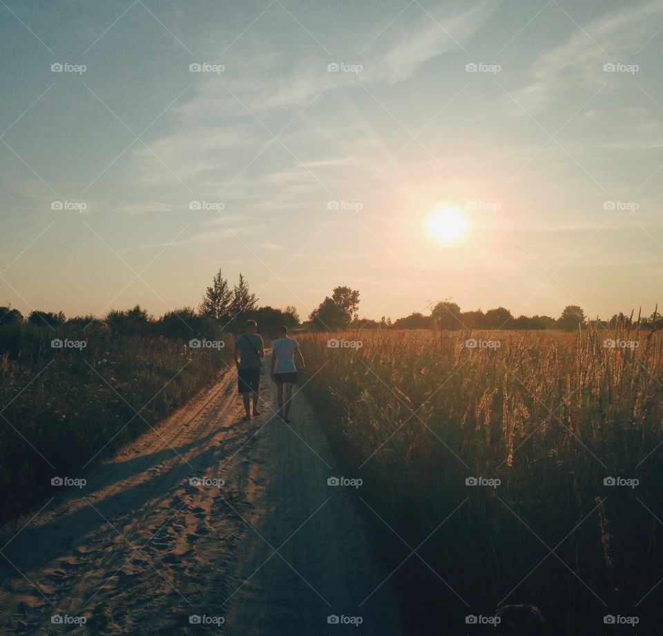 Rear view of a couple walking on dirt track