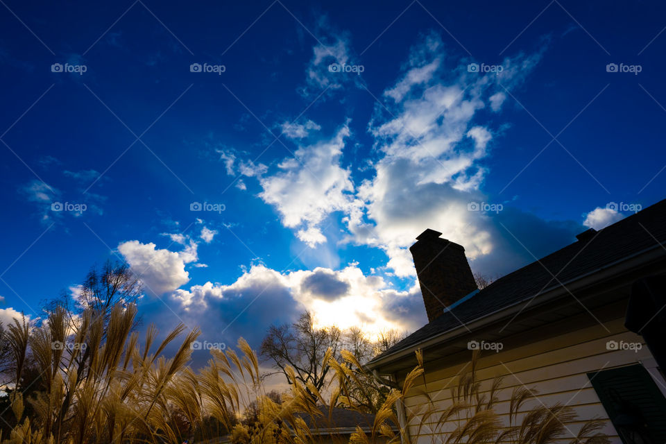 Blue sky and clouds with grass next to a house. 