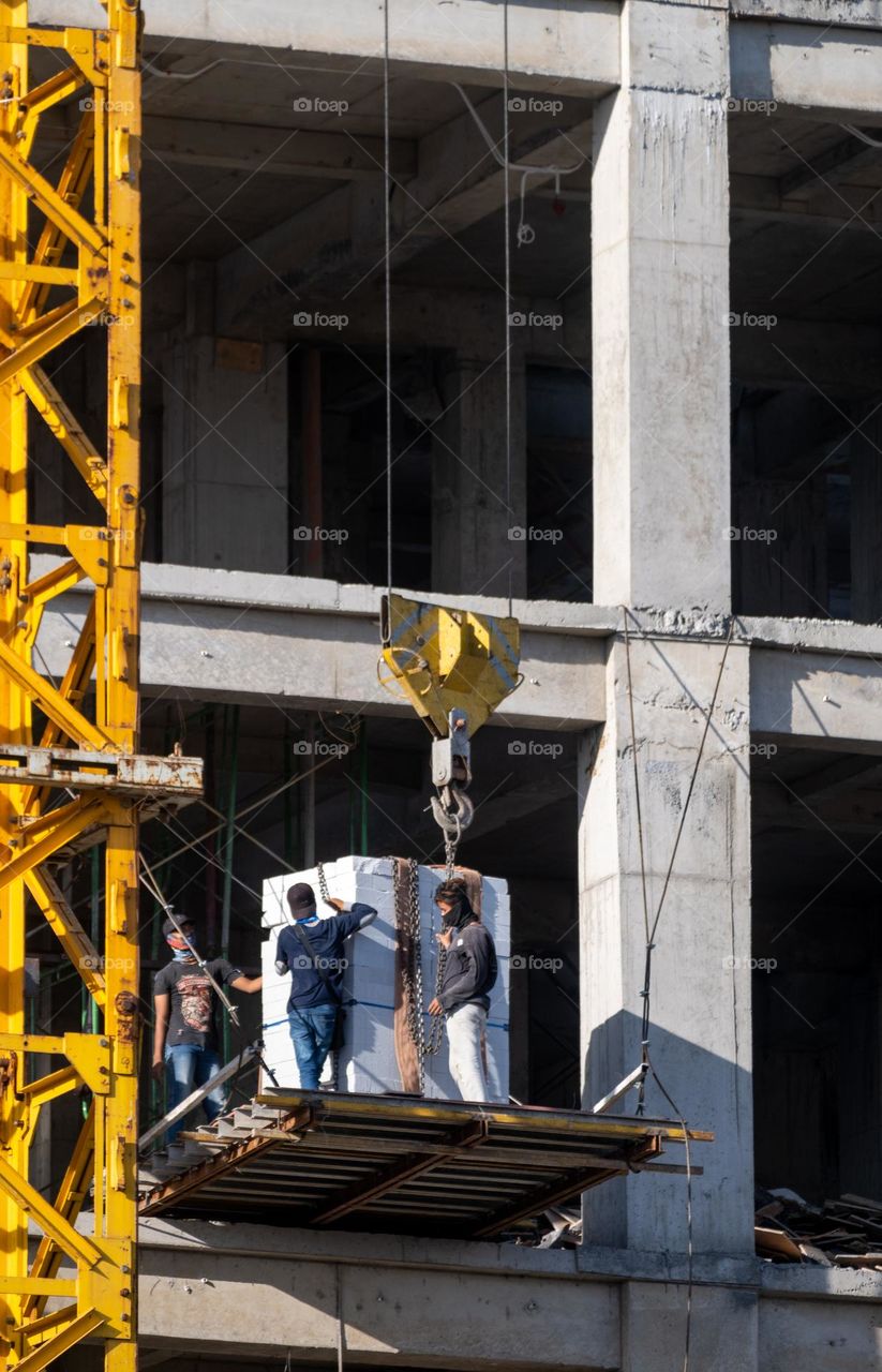 Construction workers trying to remove iron chains on a building construction project