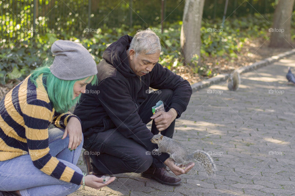 Alternative girl and old man feeding squirrels
