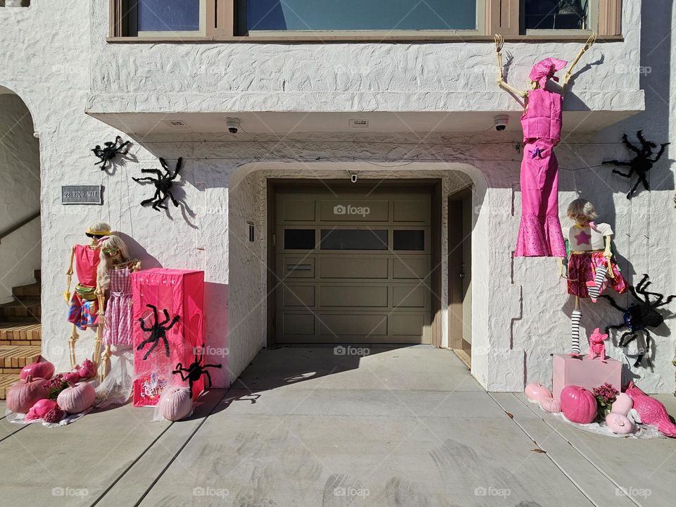 Cute and creative fall Halloween decorations in San Francisco California based on the Barbie and Ken dolls adorning a home, with vibrant pink adorned skeletons and pumpkins 