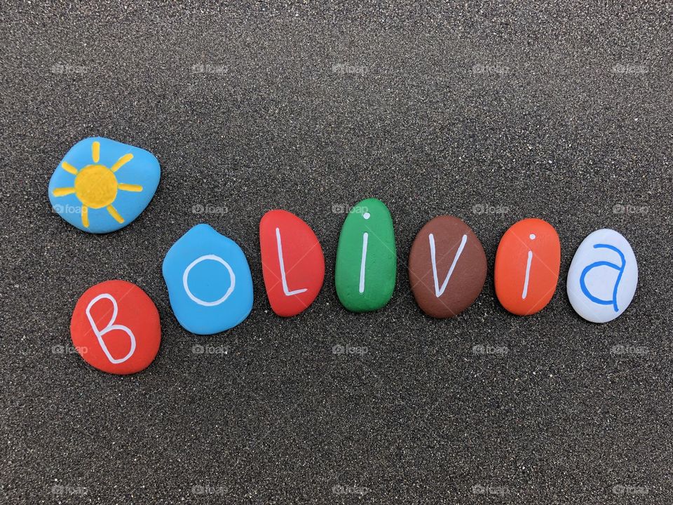Bolivia, souvenir with multicolored stones over black volcanic sand 