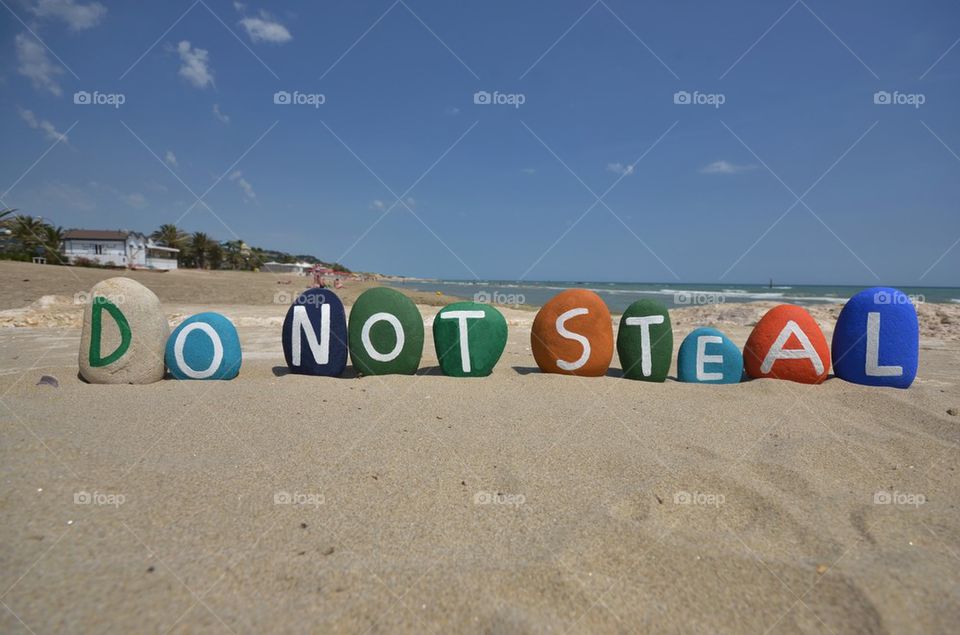 Do not steal, conceptual stones composition on the sand