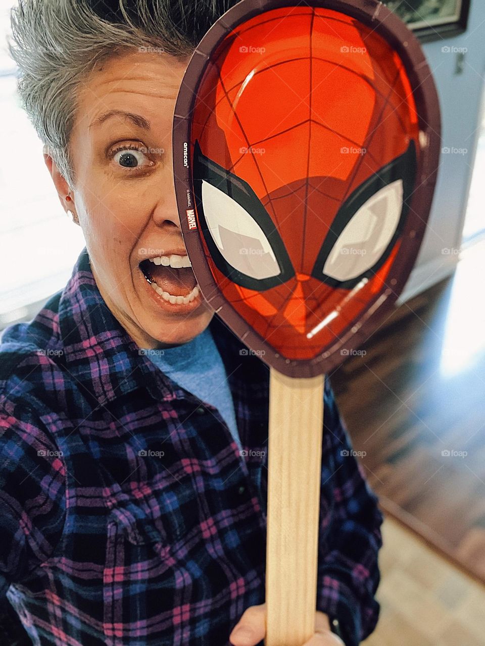 Woman acting surprised behind spider man mask, surprised woman, the emotion of surprise for a birthday party, surprise birthday party, surprise spider man birthday party, spider man mask for birthday party, element of surprise