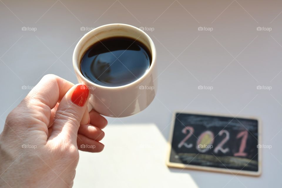 coffee cup in female hand on a white background 2021 year, morning routine