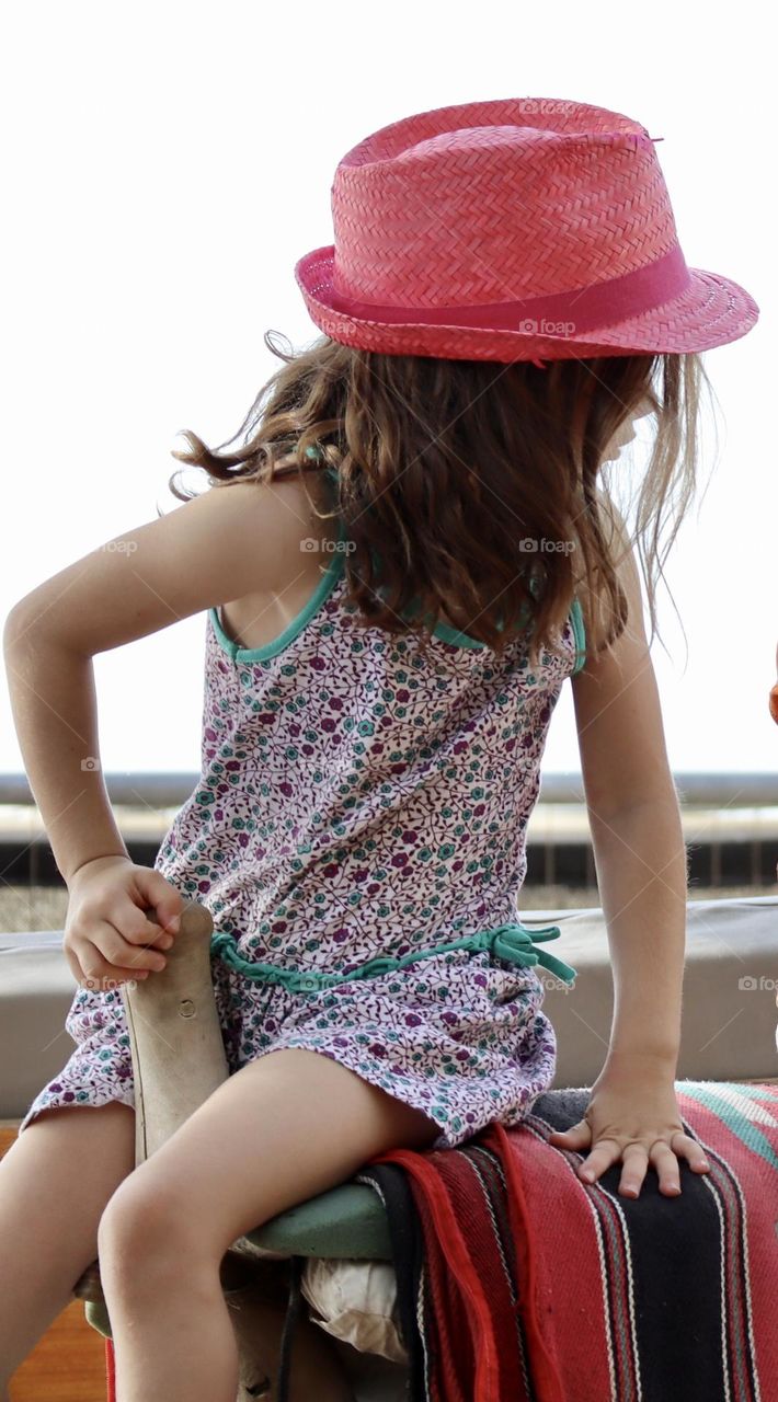 Girl with pink hat on a saddle 