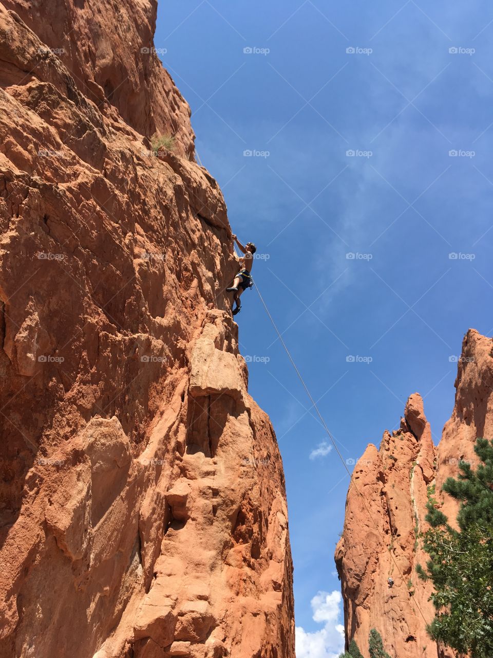 Climber on red-orange rock of Garden of the Gods against a blue cloudless sky