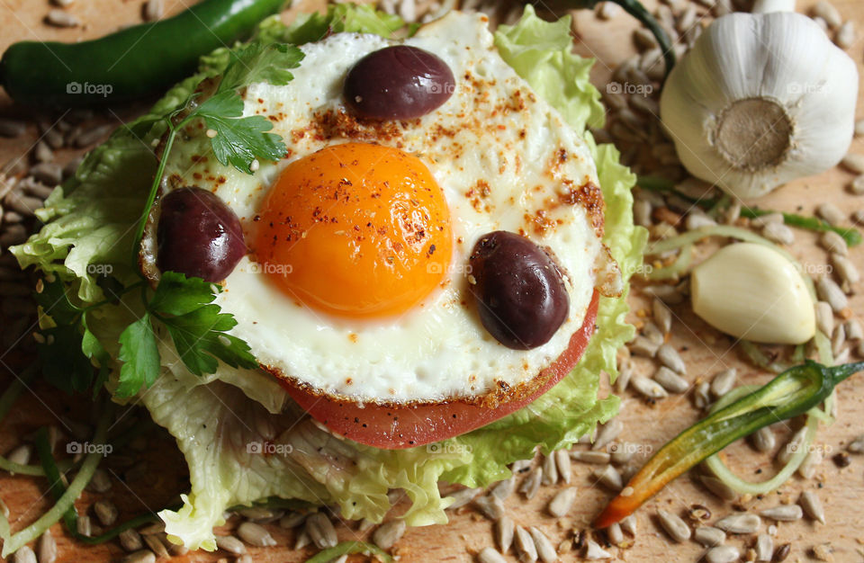 Home made burger with an egg, chilli peppers, lettuce and seeds