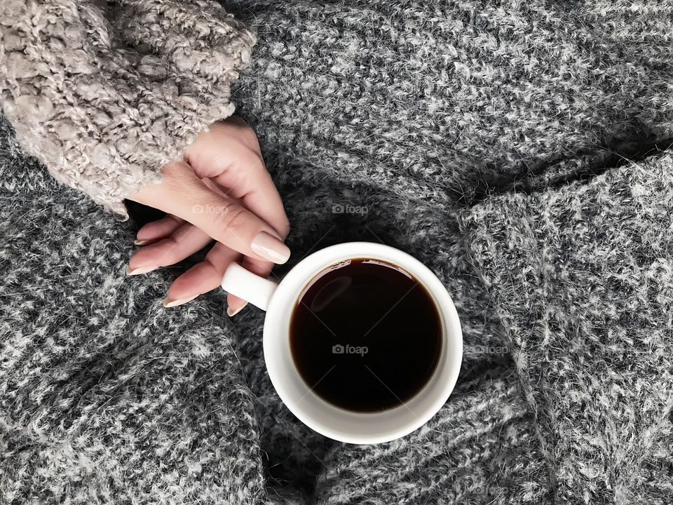 Young woman wearing cozy sweater and drinking hot coffee in winter 