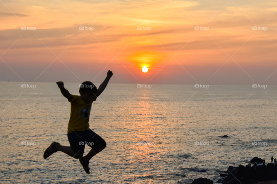 silhouette of boy jumping on the beach during sunset