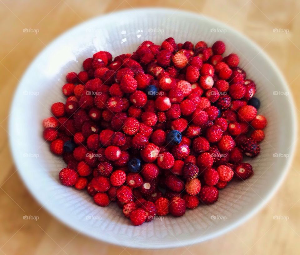 A bowl with wild strawberries and blueberries