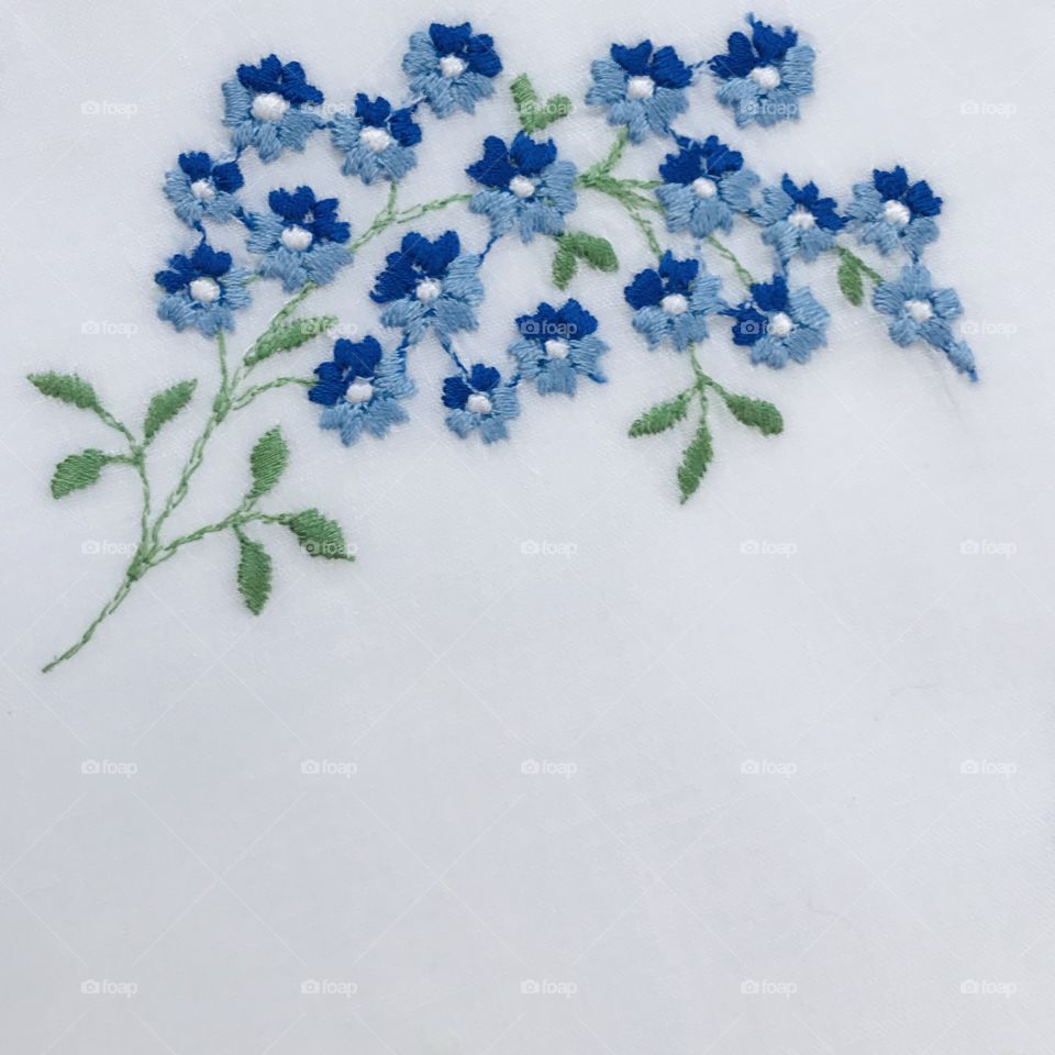 Beautiful two tone blue little flowers hand embroidery embroidered floral design with blank plain solid white empty background 
