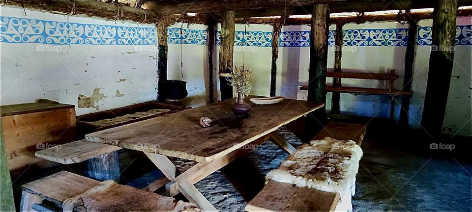 This is the inside of a house in “Gabreta”, a newly erected Celtic village after old models near the township of “Ringelai” in “Bavaria”.. A curtain with a Celtic band goes around the room with a table in the center. 2023 Hypnotic Productions