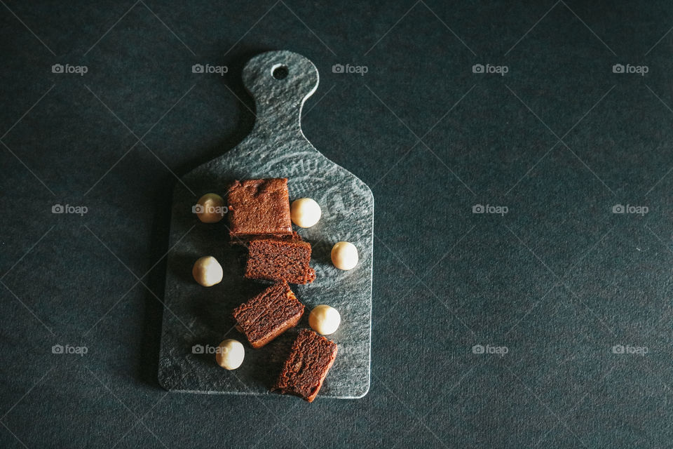 Slices of brownies and nuts served on black plate