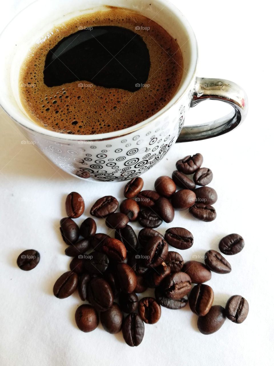 a cup of coffee with spilled coffee beans