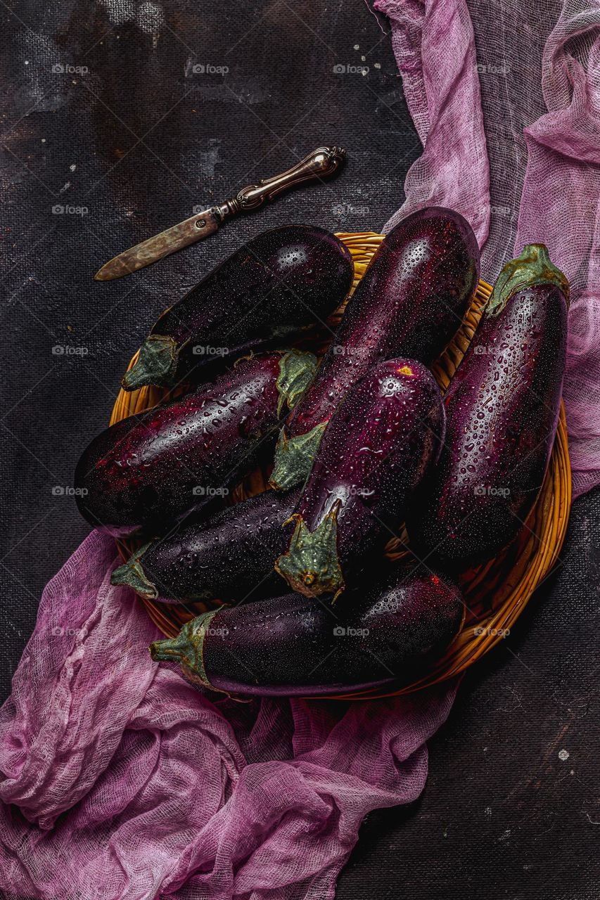 Fresh eggplants with water drops on a dark background.