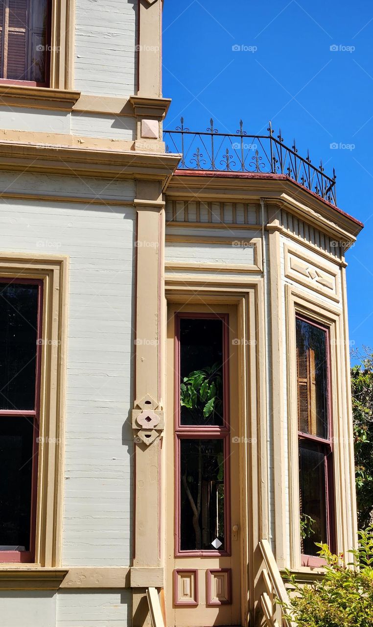 An ornate metal balcony and several windows overlook the back garden of The Flavel House in Oregon