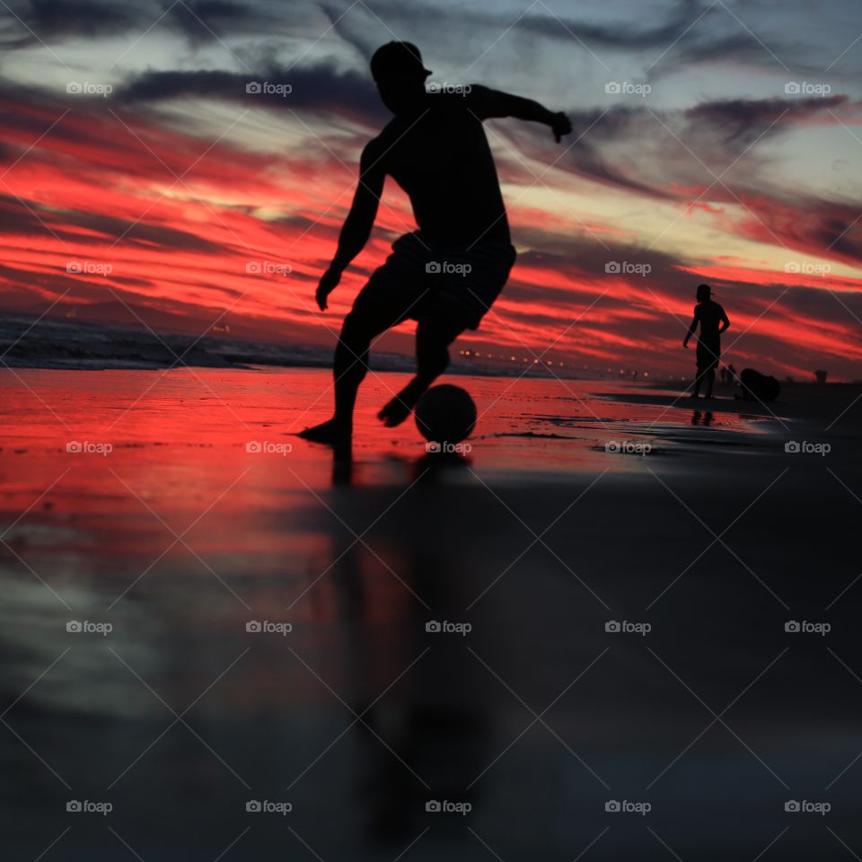 Man playing soccer at beach