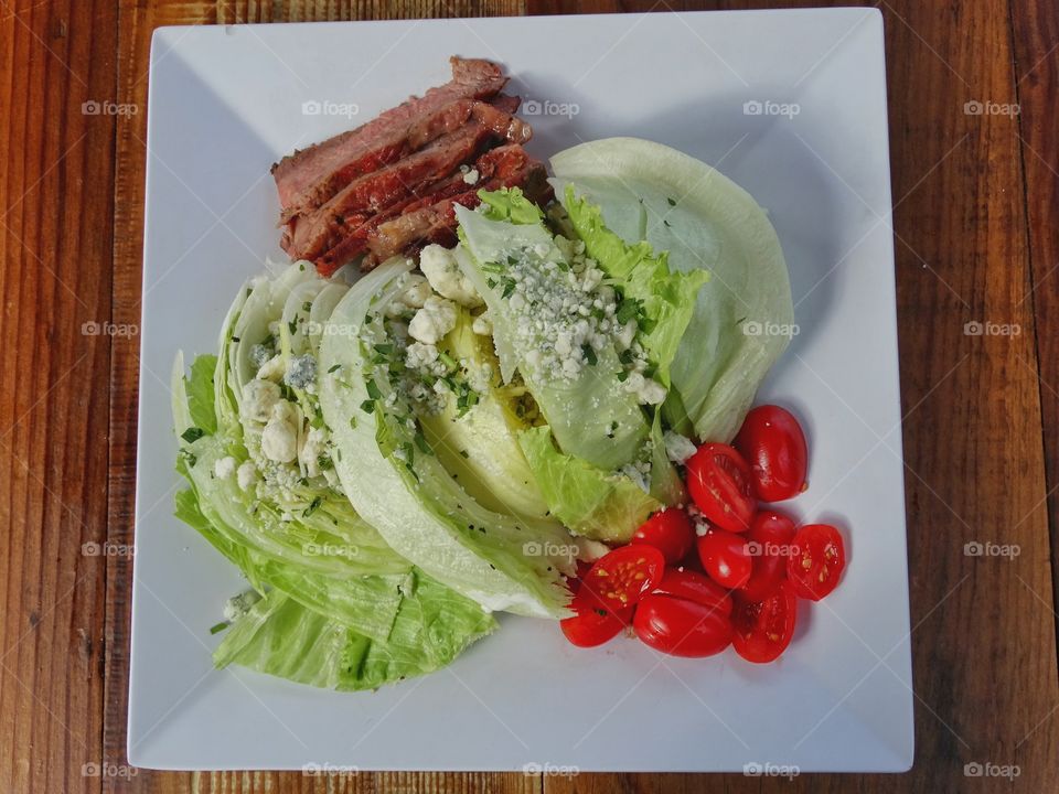 Iceberg lettuce wedge salad with steak and ripe tomatoes
