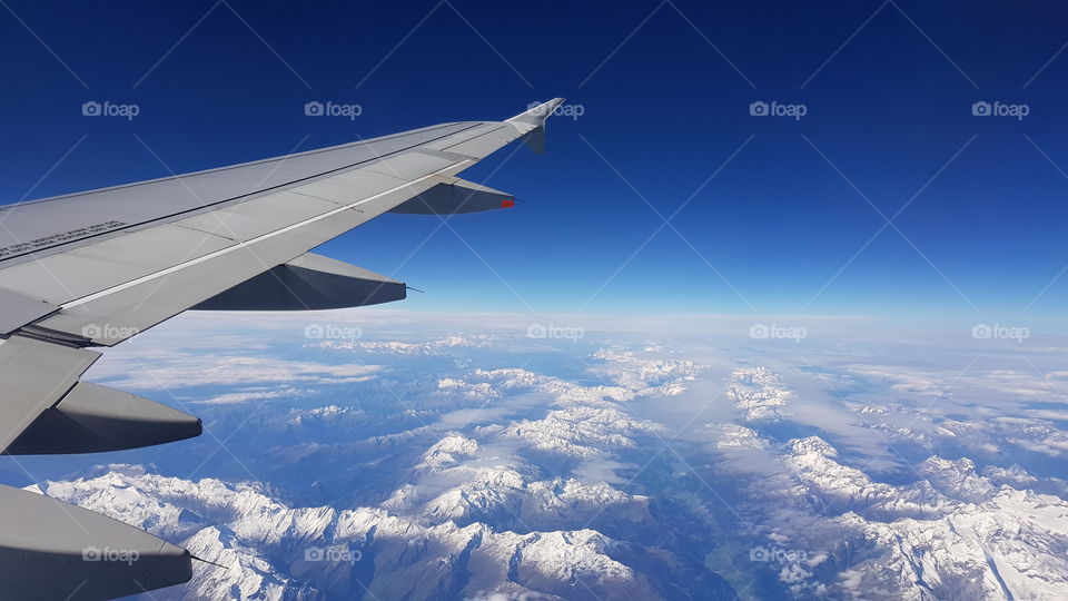 Beautiful view of the french Alps through an aircraft with blue sky