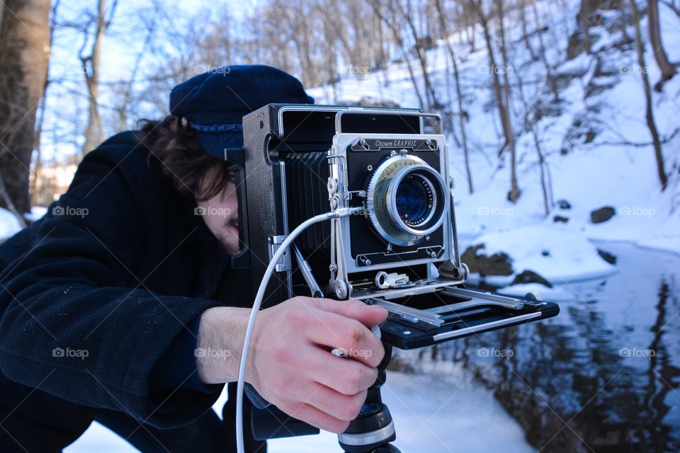 A man uses the old fashion photography equipment of a film camera to capture his image 