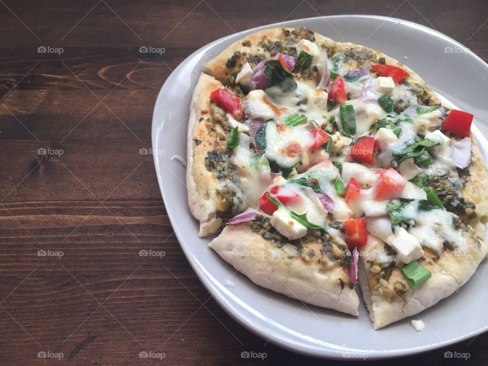 Vegetarian spring pizza with pesto sauce, red onions, red peppers, spinach, green onion and feta cheese on a whole wheat pita. A fun recipe that is tasty!