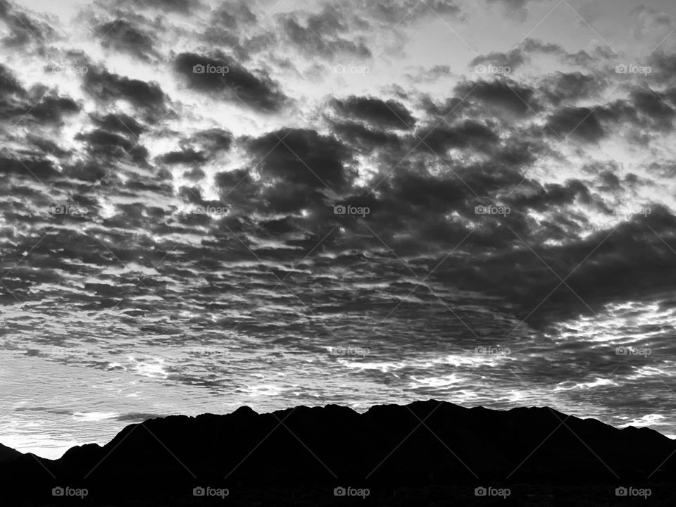 A black and white photo of a cloudy sky with mountains. 
