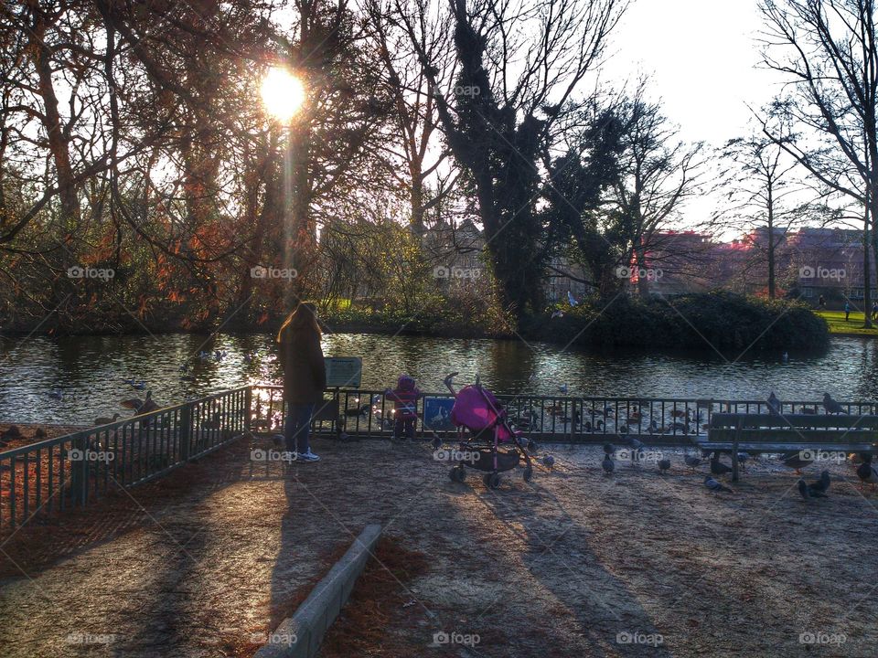 Feeding ducks in the park. Mother and daughter in Amsterdam Westerpark in autumn 2014 