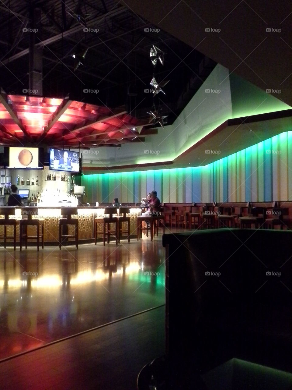 Couple and Bartender in a Colorful, Dimly Lit Bar