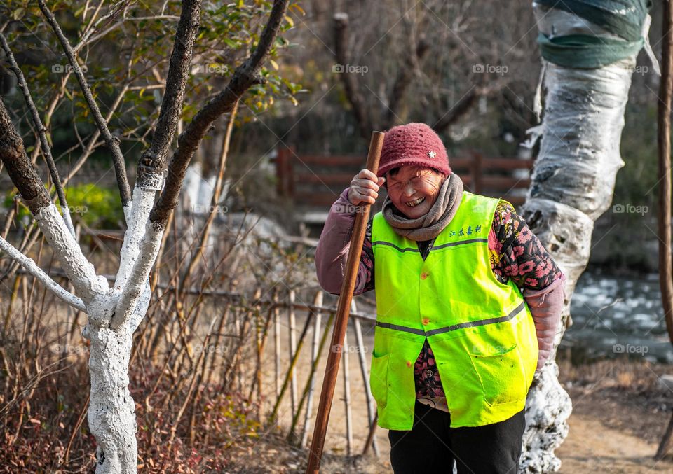 The lady is smiling while working in a garden.