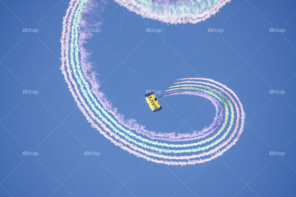 A US Navy skydiver has a colorful series of smoke canisters attached to his foot during an airshow