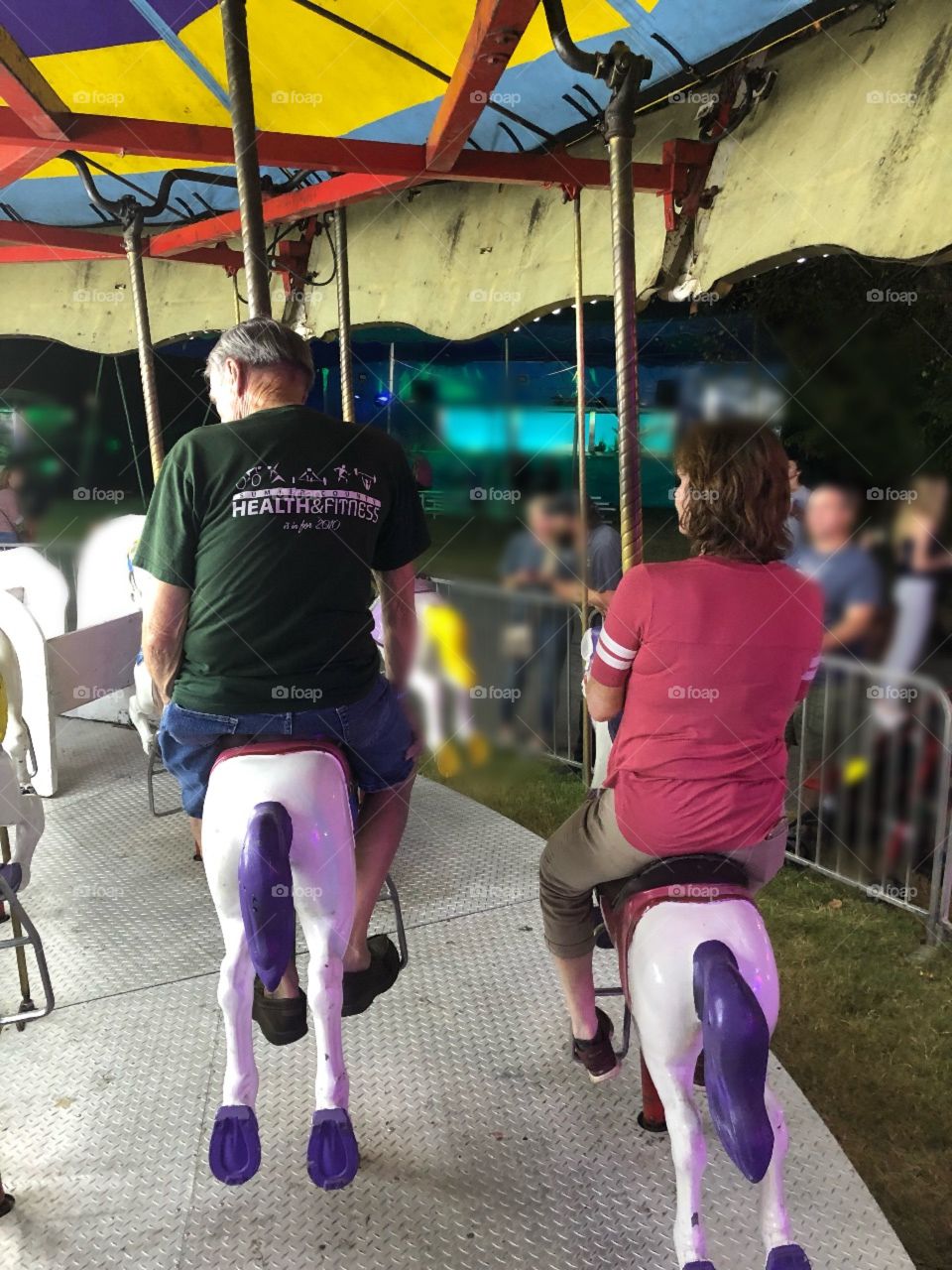Two adults enjoying the carousel at the Fair in Georgia. 