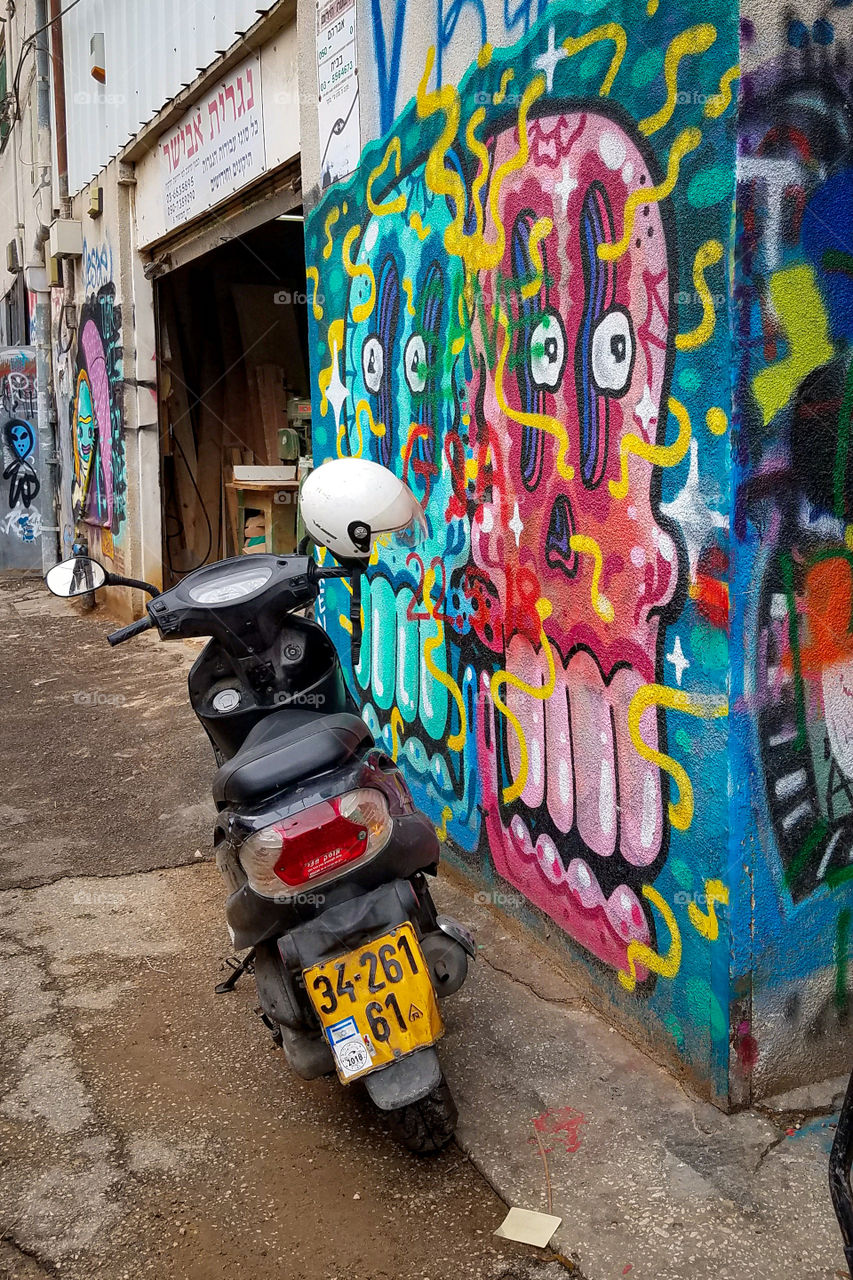 Motorbike parked on an urban city street with colorful graffiti.