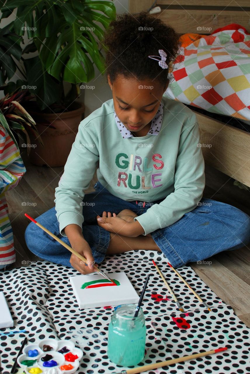 Generation Z girl of mixed race painting in an apartment living room - family  diversity teenager