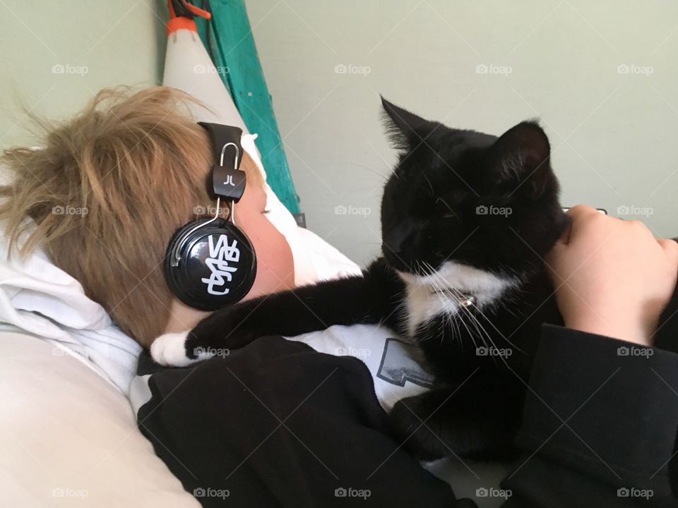 Cat takes a nap on boy with headphones 