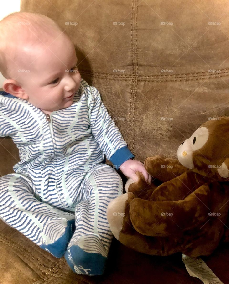 Baby loving his stuffed monkey.