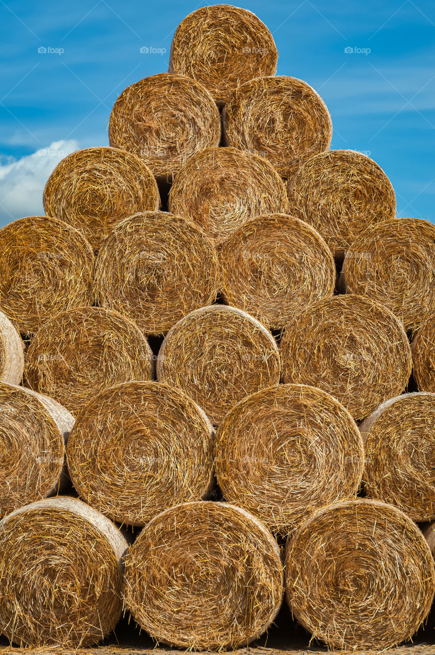 Close up at round bales of hay stacked on top of each other forming a piramide shape.