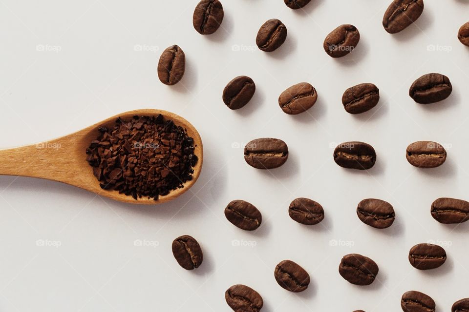 A spoonful of coffee powder and coffee beans