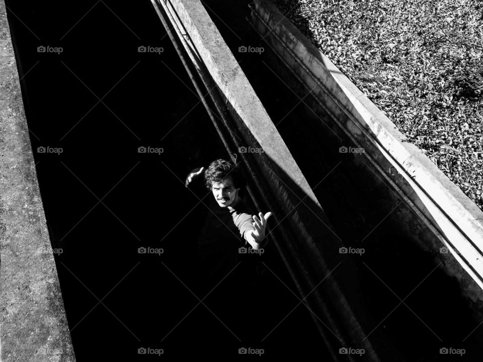 Black and white photo of a man in the shadows. Beautiful harsh natural lighting.