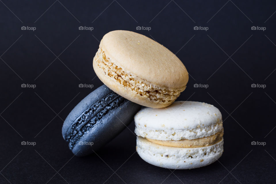 Black, white and brown colours macaroons in black background 
