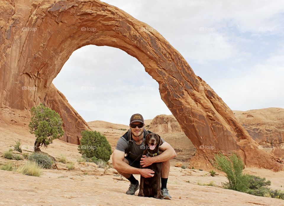 A man and his dog pose for a photo while hiking in Moab, Utah on a beautiful spring day. 