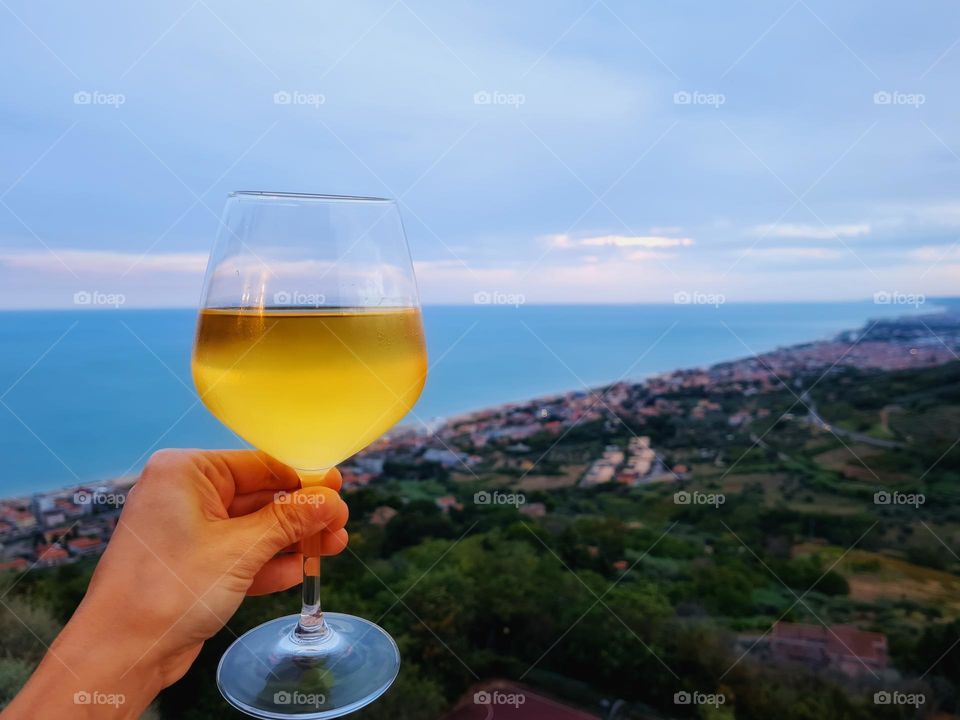 hand holds a glass of white wine on the Silvi viewpoint